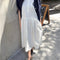 model wearing white cotton midi dress with henley button neckline and drop waist and blue cardigan