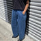 model wearing blue denim relaxed fit pants with black tee