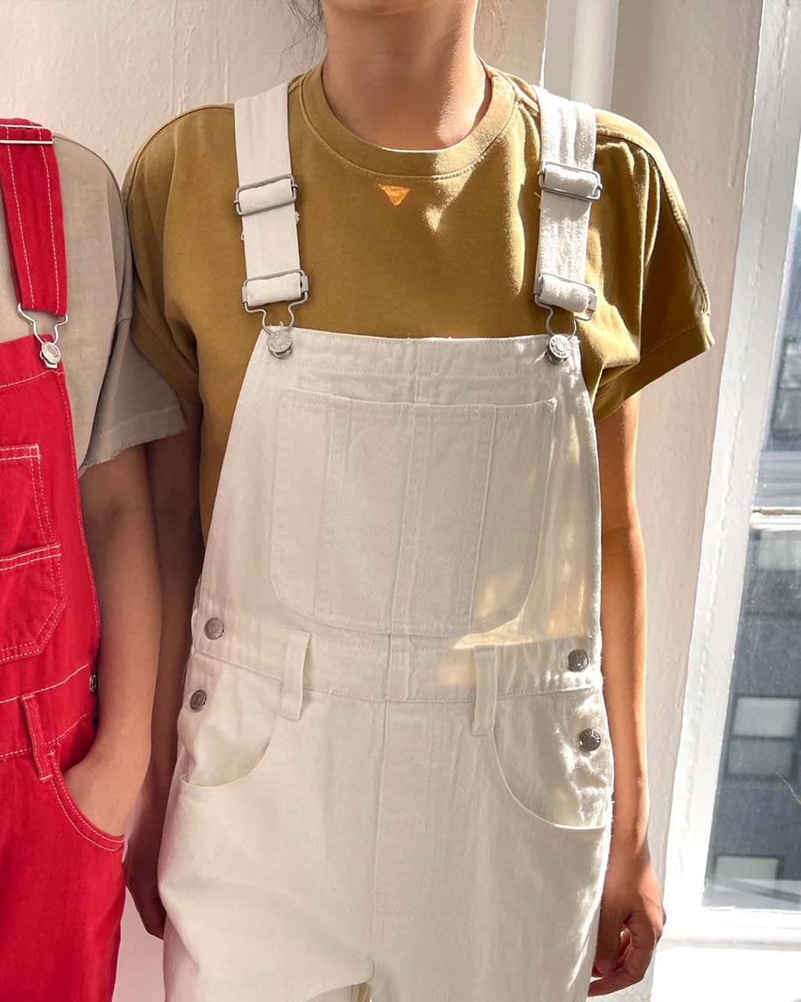 model wearing butterscotch relaxed fit vintage tee under white overalls