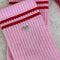 up close of pink high crew socks with two red stripe top and silver embroidered heart