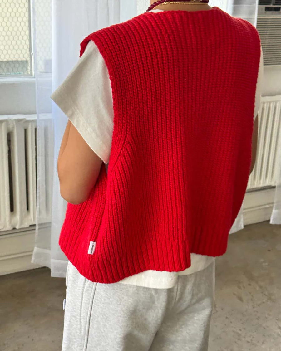 back view of model wearing red knit open front 'granny' sweater vest