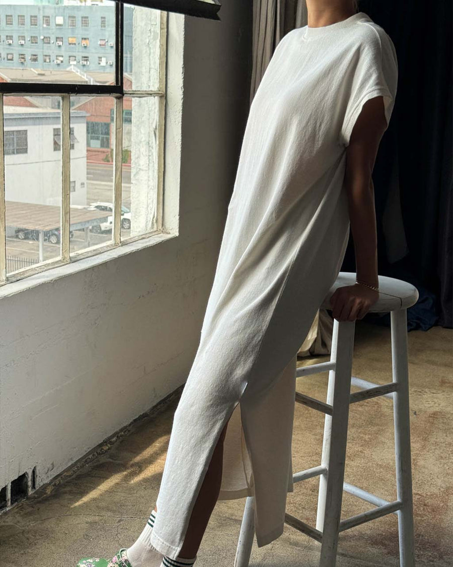 side view of model wearing cream cotton maxi dress with muscle sleeves and side slits