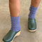model wearing high crew fuzzy lavender socks with green clogs