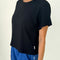 side view of model wearing black relaxed fit tee with a slight crop