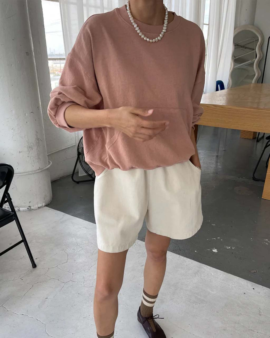 model wearing macchiato cotton long sleeve top with kangaroo pocket front and cream shorts