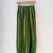 avocado green cotton balloon pants with side pockets on a hanger