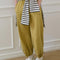 model wearing ochre yellow cotton balloon pants and white and black striped sweater around their waist