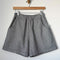 thin navy and white stripe shorts with side pockets and exposed hem at the bottom on a hanger