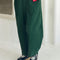 model wearing dark green corduroy arc pants with side panels and pockets