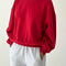 model wearing bright red pull over sweatshirt with slight balloon sleeve and waist band