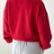 back view of model wearing bright red pull over sweatshirt with slight balloon sleeve and waist band