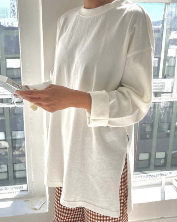 model wearing white cotton tunic top with deep side slits and long sleeves