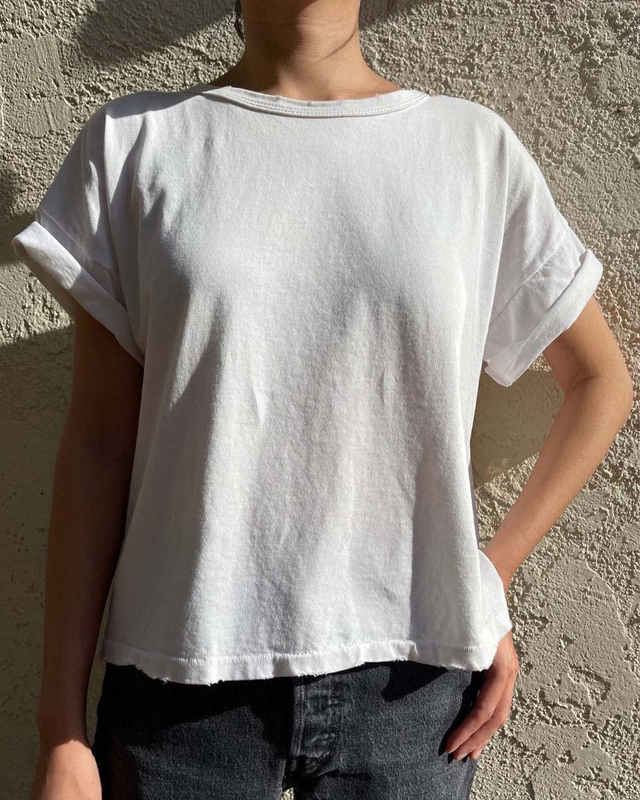 model wearing relaxed, slightly cropped clean white tee with distressing on the neckline