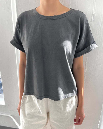 model wearing relaxed, slightly cropped washed black tee with distressing on the neckline
