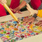 models holding a large pencil over le puzz 500 piece puzzle with colorful erasers