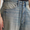 up close of model wearing gritty medium wash loose crop button fly jeans with distressing on the legs