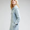sideview of model wearing light denim long sleeve unionall with slit pockets, button front and collar