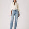 model wearing medium denim slightly relaxed straight leg jeans with cream blouse