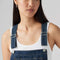 up close of model wearing relaxed fit dark blue overalls with a white tank