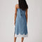 back view of model wearing light denim slip dress with side slits and scalloped lace hem