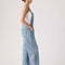 side view of model wearing light denim relaxed fit overalls with front pockets