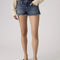 model wearing dark denim low rise shorts with frayed hem