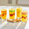 set of 4 vintage inspired fruit glasses: cherry, orange, strawberries and lemon filled with orange beverage