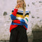 model wearing primary color mockneck tunic with white, blue, black, yellow, green, blue and red different sized stripes