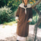 model wearing brown oversized trench coat with white and dainty blue folk print tie shawl, arm and hem trim