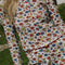 up close of model wearing white cotton cardigan with red lettuce trim, red button front, and retro primary color floral print
