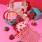 set of 7 strawberry, gingham and red makeup erasers with wash bag and checkered hair clip surrounded by strawberries
