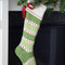 green and white stripe cotton stocking with cream cuff, red box and red dot detail hanging from a fireplace