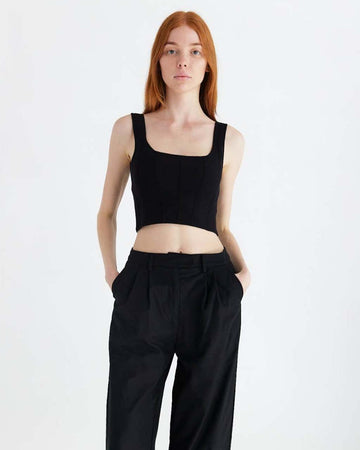 model wearing black structured sleeveless crop top with piping detail