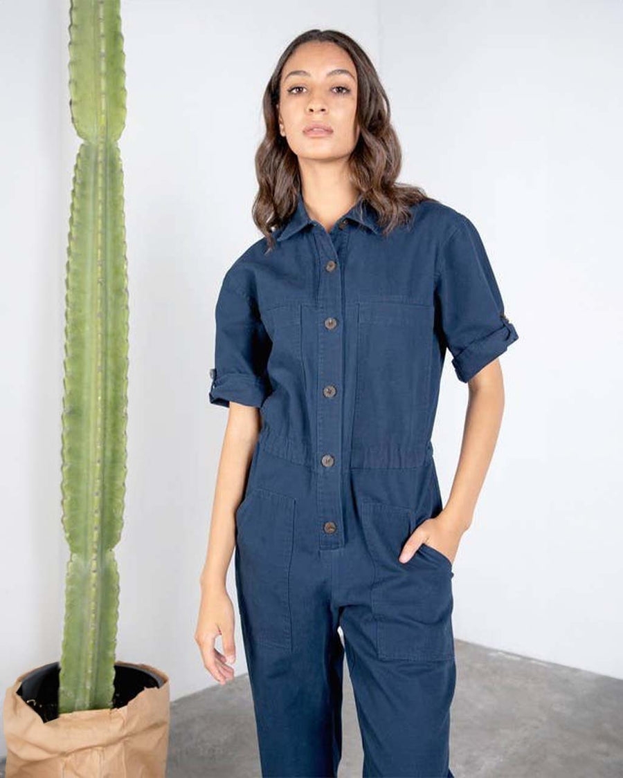 up close of model wearing dark blue short sleeve jumpsuit with cinched waist and button front