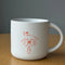 white ceramic mug with orange person holding a horse with 'HOLD UR HORSES' on it on a table
