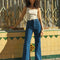 model wearing high waisted dark denim flare jeans and white tank