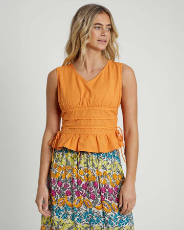 model wearing orange peplum top with lace detail on the waist and side ties