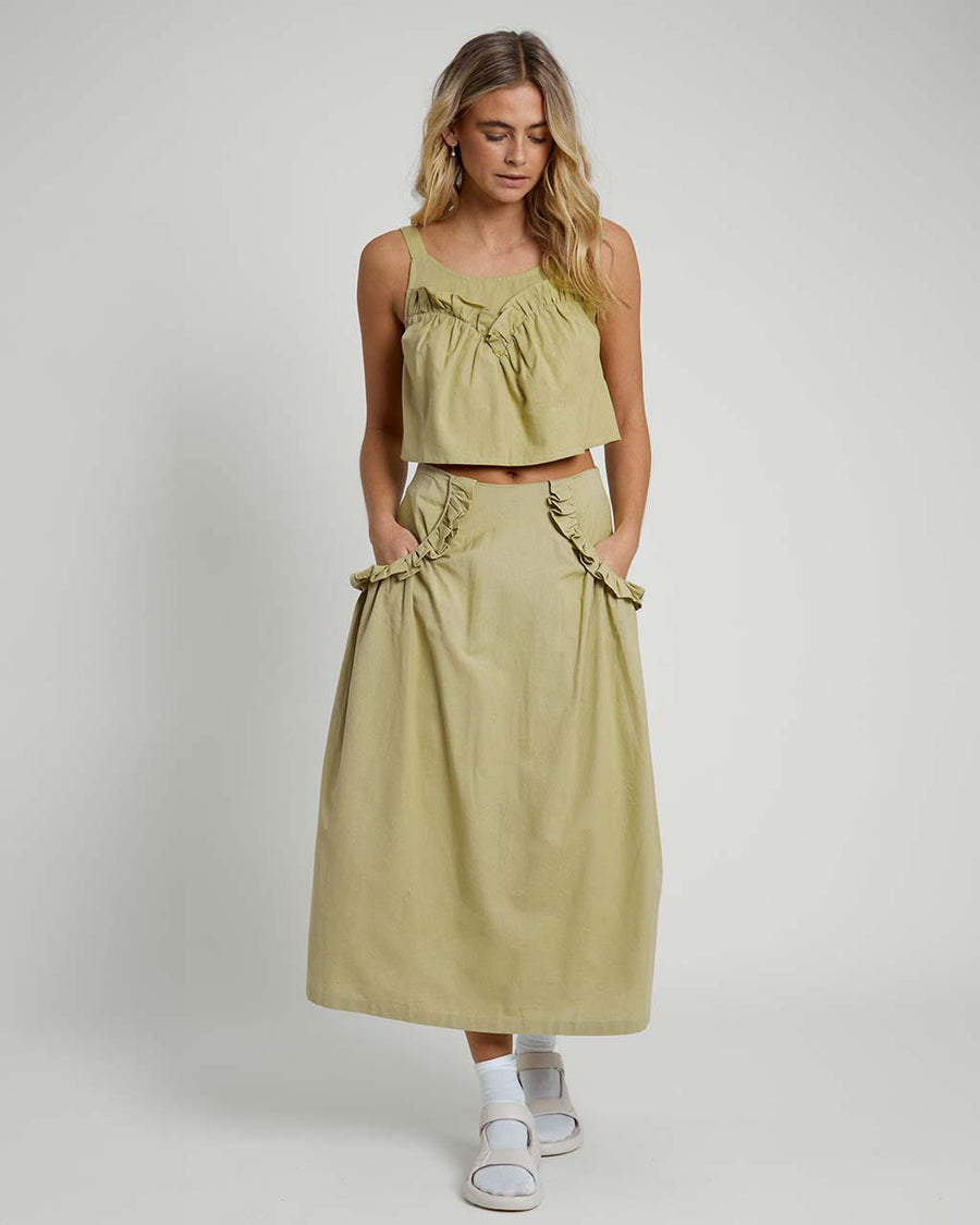 model wearing moss midi skirt with rounded ruffle detail on the hips and matching top