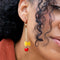 up close of model wearing dangle earrings with bow-tie pasta and tomato charms