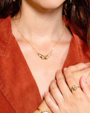 model wearing gold necklace with two holding hands