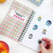 model putting fruit stickers inside of 'my super special collection of fruit stickers' journal book