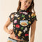model wearing black fitted mesh top with ruffle sleeves and all over pasta and veggie print