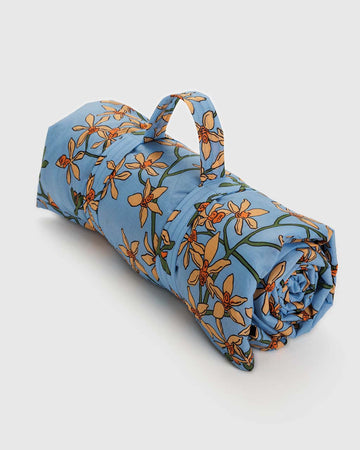rolled up blue puffy picnic blanket with yellow orchid print