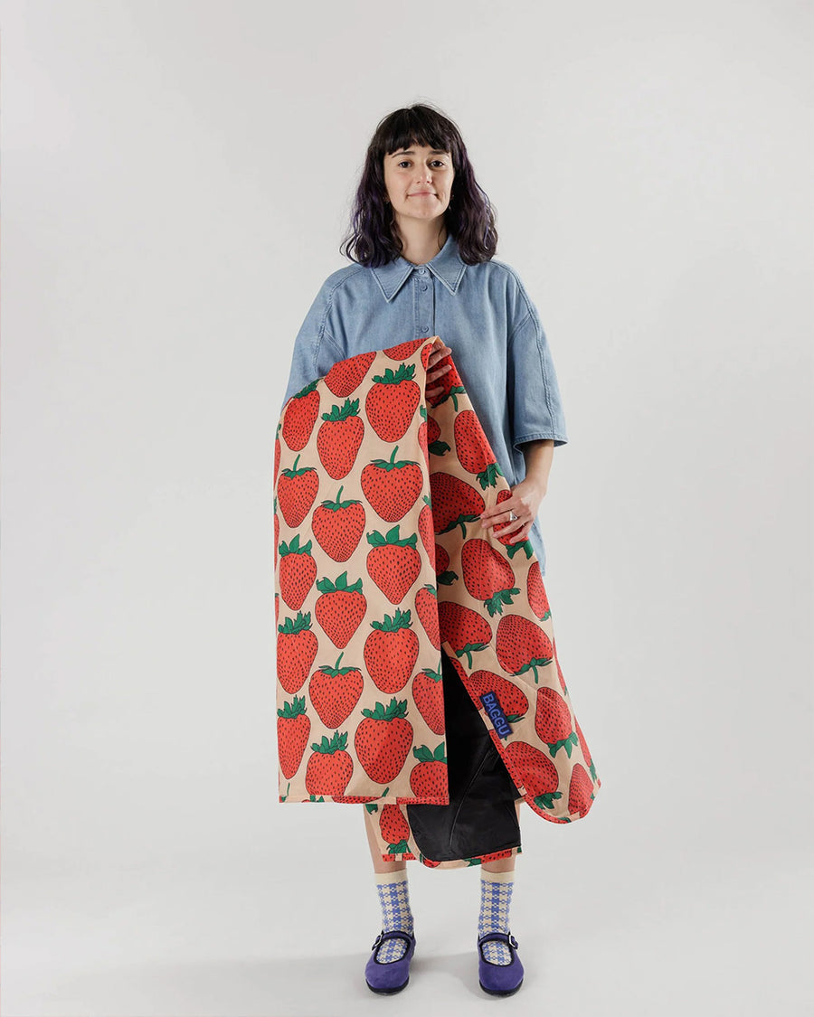 model holding pink puffy picnic blanket with large strawberry print