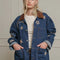 model wearing denim oversized jacket with corduroy collar, patch pockets, and embroidered star, moon and sun pattern