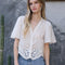 model wearing white scalloped hem blouse with slight puff sleeves and faux button front
