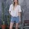 model wearing white scalloped hem blouse with slight puff sleeves and faux button front