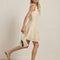 side view of model wearing cream lace mini dress with faux button front detail