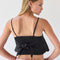 back view of model wearing black handkerchief tank with eyelet floral detail and tie detail