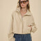 model wearing zipped light khaki cropped jacket with stand up collar and elastic bottom